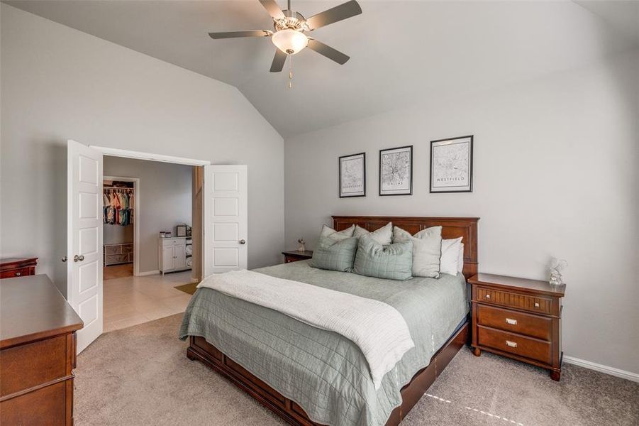 Bedroom with a walk in closet, 11' sloped ceiling, ceiling fan, and light colored carpet