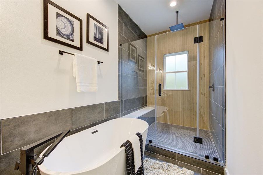 Primary Bathroom. Features soaker tub and custom tiled oversized shower with ribbon oak tile accent wall!