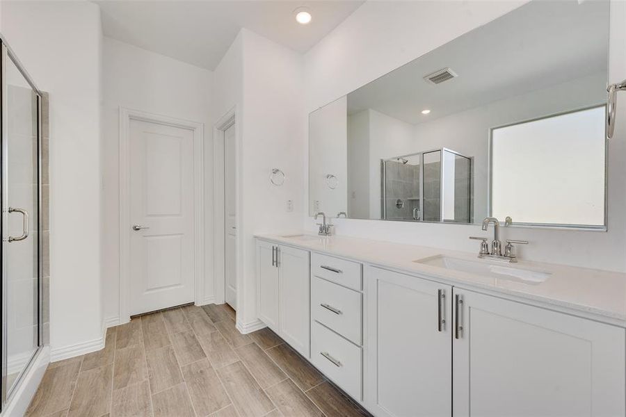 Bathroom featuring a shower with door, vanity, and wood-type flooring