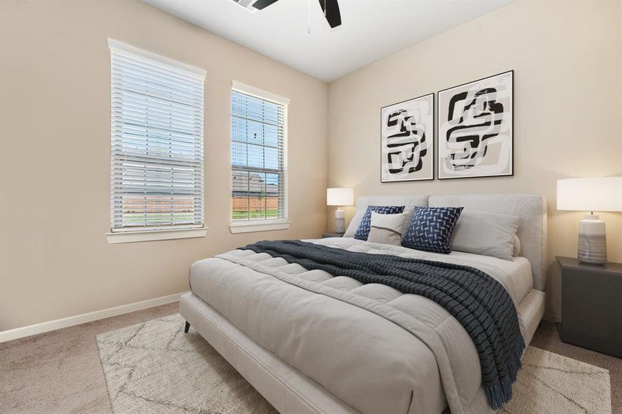 Secondary bedroom features plush carpet, neutral paint, dark stained ceiling fan with lighting and large windows with privacy blinds.