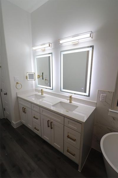 His and her's vanity sinks in primary bathroom w/ LED backlit/frontlit function with defog feature. Brushed gold hardware, brushed gold faucets, brushed gold sink drains, brushed gold light fixtures, and brushed gold make-up mirror for the most fashion conscious person.