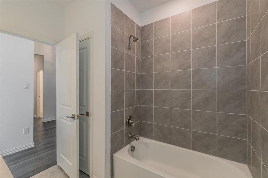 Bathroom with tiled shower / bath combo and hardwood / wood-style flooring