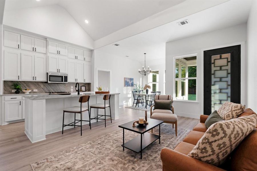 Living room featuring light hardwood / wood-style floors, high vaulted ceiling, a notable chandelier, and sink