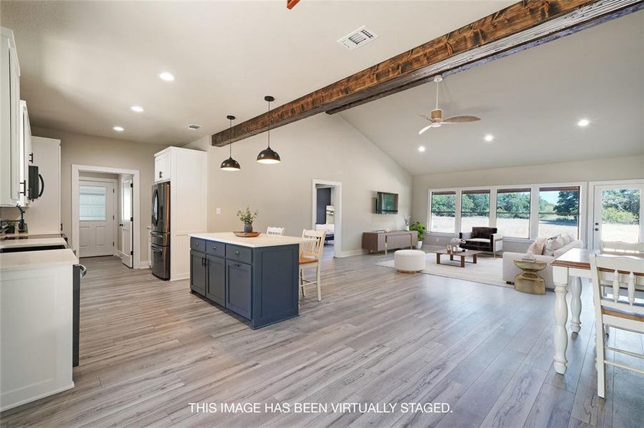 Kitchen featuring light wood-type flooring, stainless steel fridge, ceiling fan, hanging light fixtures, and beam ceiling