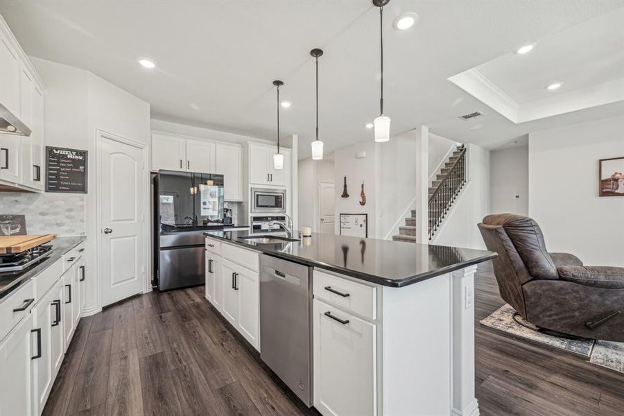 Kitchen featuring white cabinets, an island with sink, dark hardwood / wood-style floors, backsplash, and appliances with stainless steel finishes