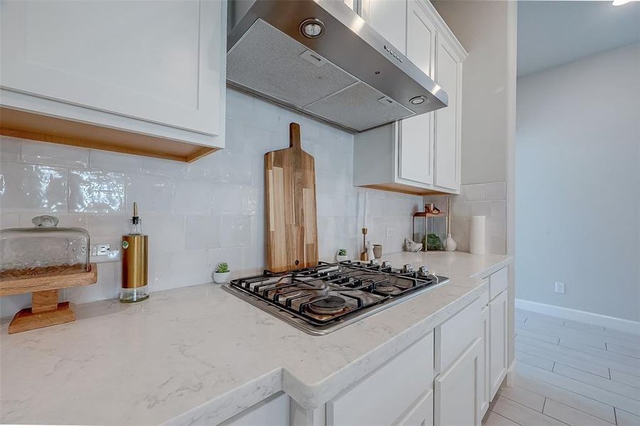 The kitchen has tile backsplash and a gas cooktop.