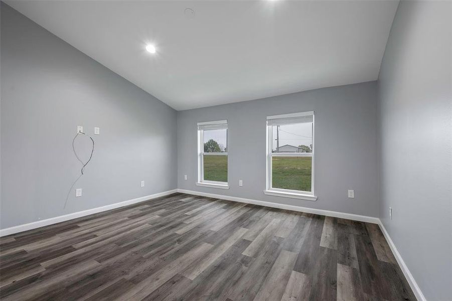 Spare room featuring lofted ceiling and dark hardwood / wood-style floors