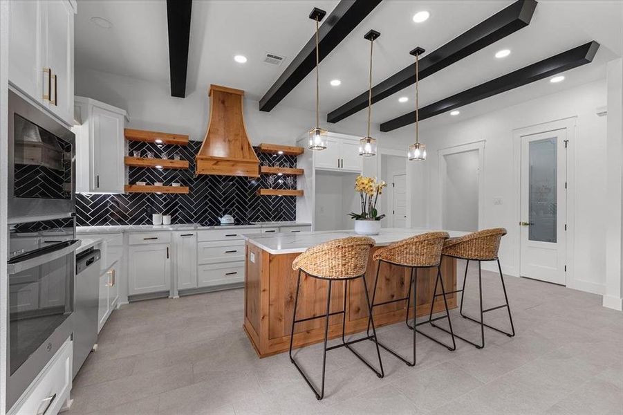 Kitchen featuring beam ceiling, tasteful backsplash, a kitchen island, white cabinetry, and appliances with stainless steel finishes