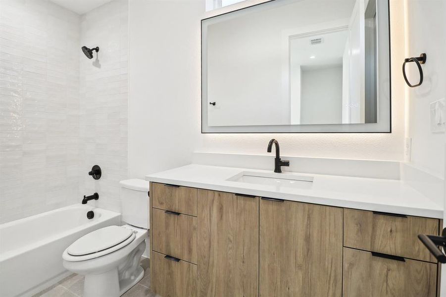 Full bathroom with vanity, toilet, tiled shower / bath combo, and tile patterned flooring