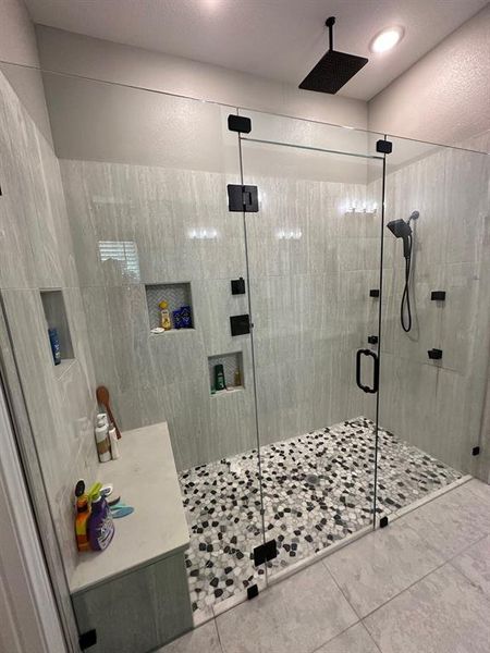 Bathroom with tile floors, walk in shower, and tile walls