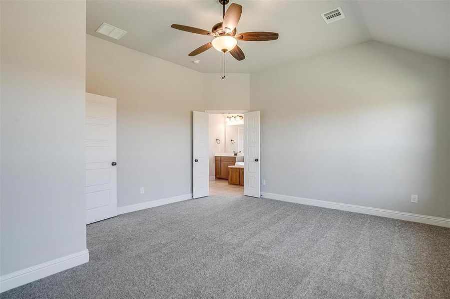 Unfurnished bedroom featuring ensuite bath, ceiling fan, high vaulted ceiling, and light colored carpet