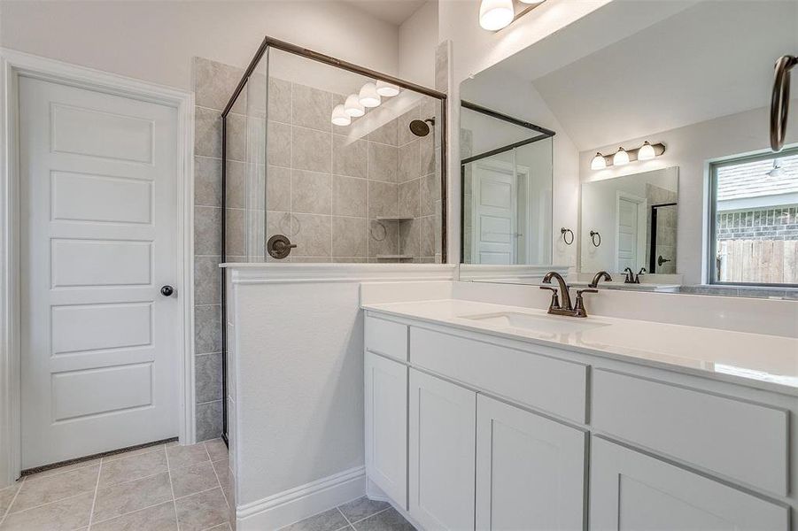 Bathroom featuring vanity, tile patterned flooring, lofted ceiling, and tiled shower