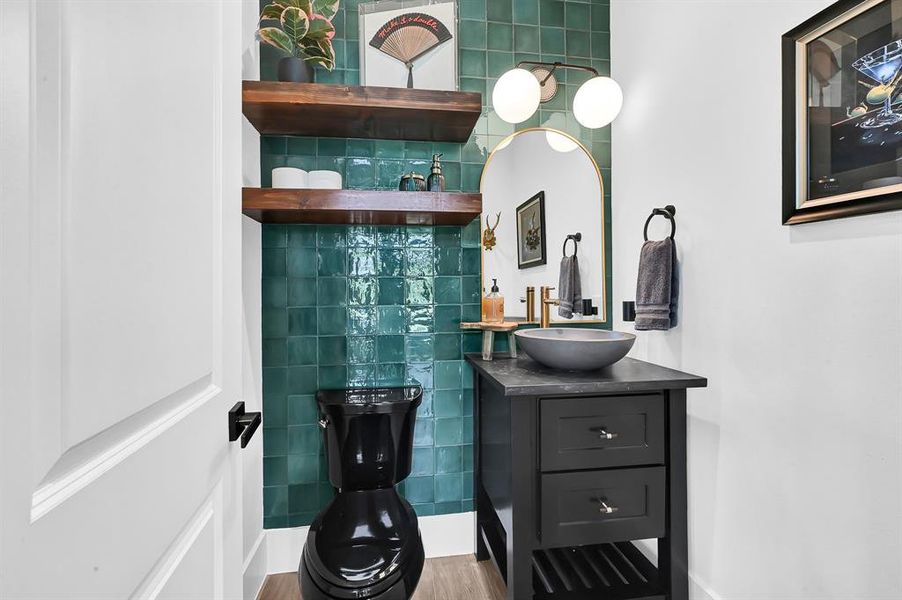 Chic half bath with striking emerald accent wall, nestled in a versatile entertainment room.