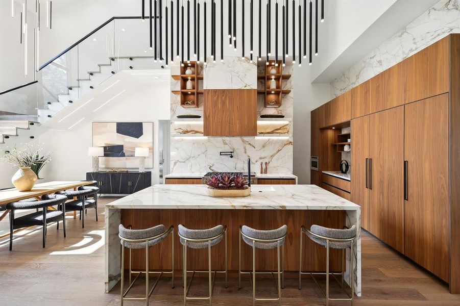 Chef's kitchen featuring large porcelain island with mitred waterfall edge and GE Monogram appliances.