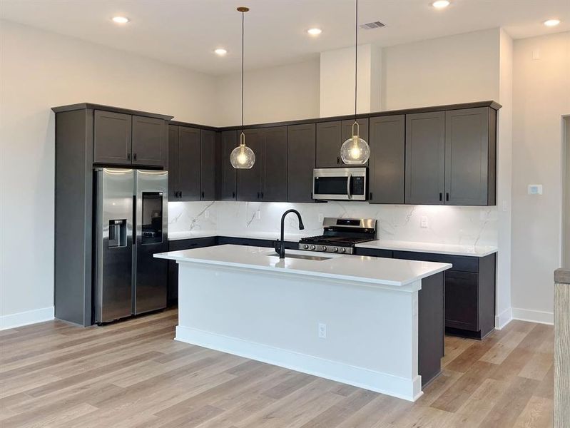 Modern Chef's Kitchen with sleek dark cabinetry, stainless steel appliances, and an inviting central island under elegant pendant lighting.