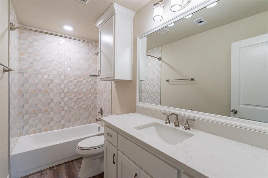 Full bathroom with stone vanity, and tiled shower / bath, cabinets to the ceiling