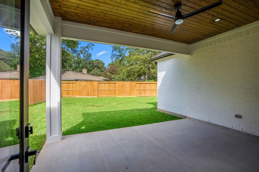 Oversized back patio with lounge and groove ceilings.