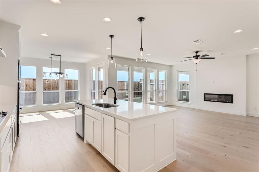 Kitchen with a center island with sink, sink, decorative light fixtures, stainless steel dishwasher, and white cabinets