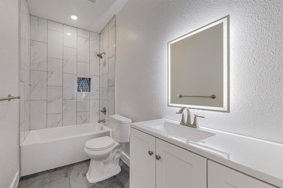 Full bathroom featuring tile floors, toilet, tiled shower / bath, and oversized vanity