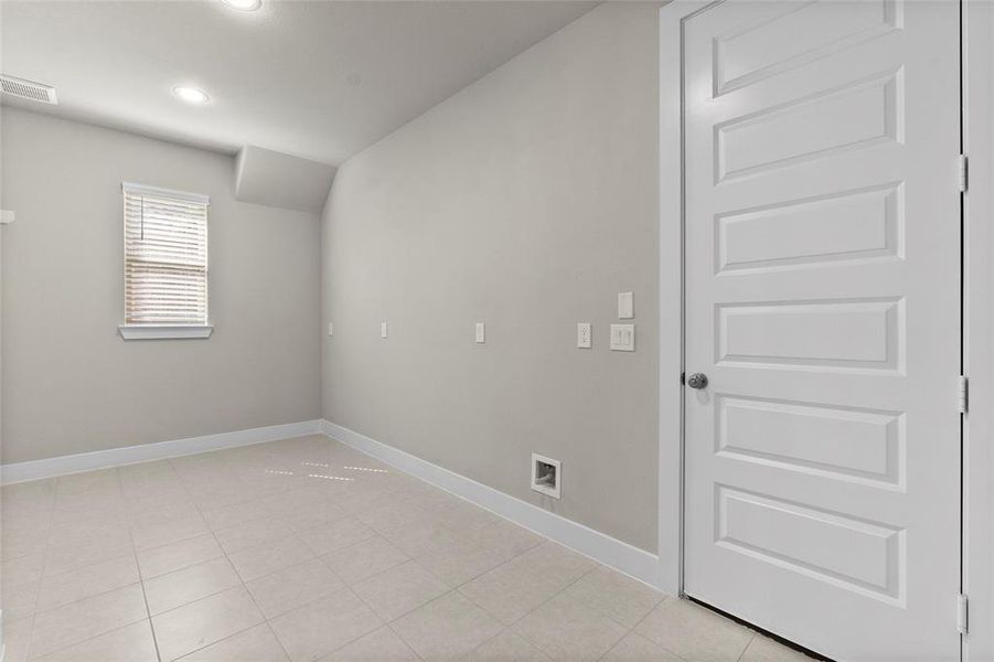 This view of the laundry room really shows off its size! It also includes a gas line for multiple possibilities, and behind the door is the garage with three full bays for parking or storage.