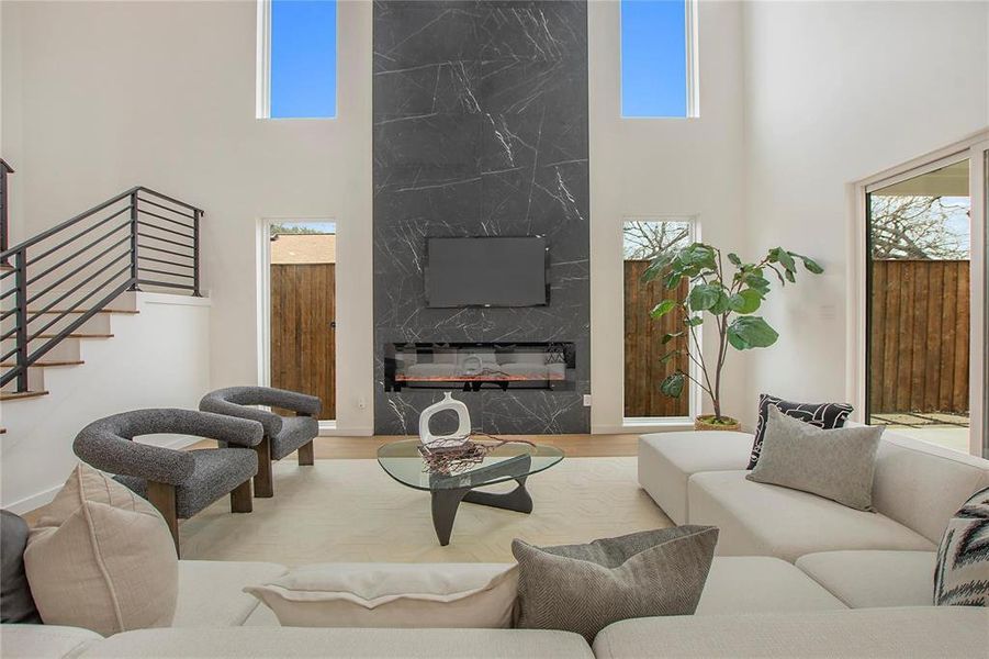 Living room with light hardwood / wood-style floors, a high ceiling, and a wealth of natural light