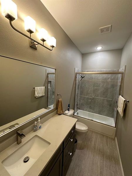 Full bathroom featuring tiled shower / bath, a textured ceiling, hardwood / wood-style flooring, toilet, and vanity