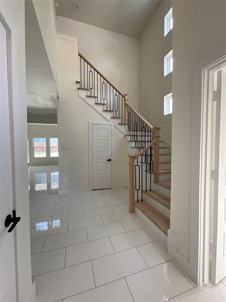 Stairs featuring light tile patterned floors and a high ceiling