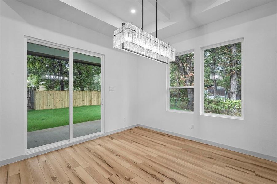 Unfurnished dining area featuring an inviting chandelier and light hardwood / wood-style flooring