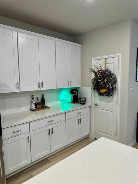 Kitchen featuring light wood-type flooring, white cabinetry, and tasteful backsplash