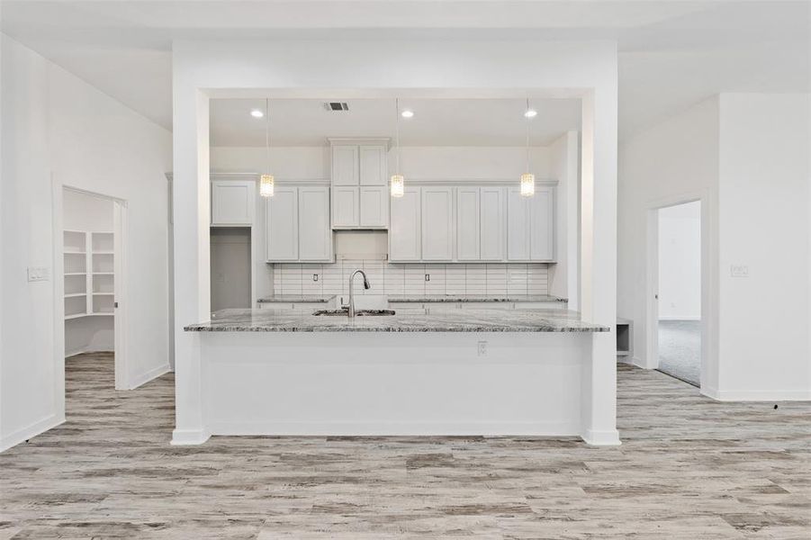 Framed kitchen island granite countertop light gray cabinets.