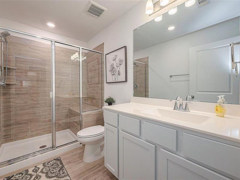 This updated bathroom features a clean design with a shower, toilet and sink.