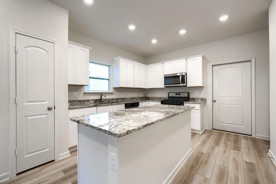 Kitchen featuring sink, appliances with stainless steel finishes, a center island, and white cabinets