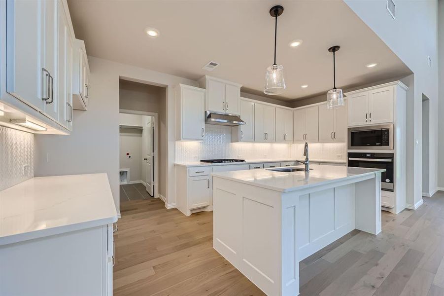 Kitchen with sink, white cabinets, stainless steel appliances, and light hardwood / wood-style floors