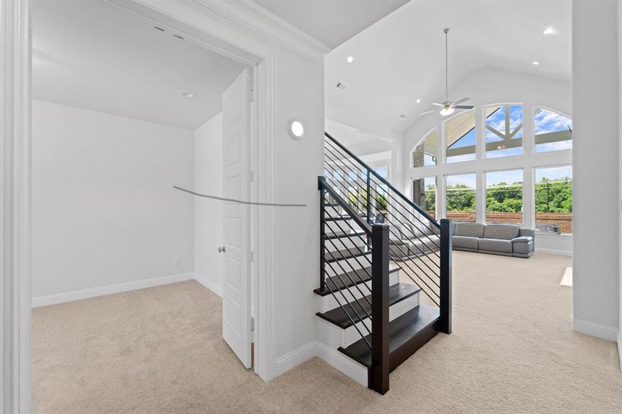 Staircase featuring light carpet, ornamental molding, ceiling fan, and vaulted ceiling