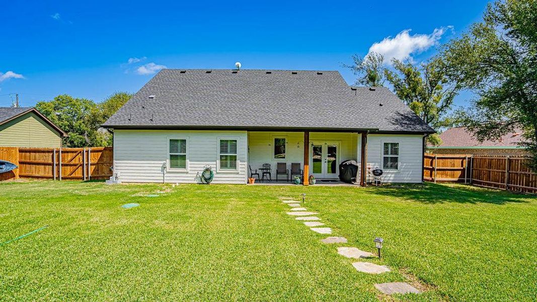 Rear view of property featuring a lawn and a patio area