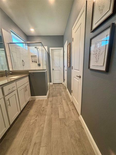 Bathroom featuring hardwood / wood-style flooring, a shower with door, and vanity