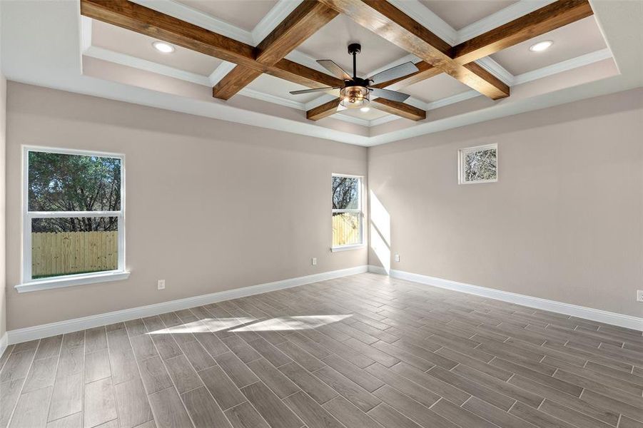 Unfurnished room featuring a wealth of natural light, ceiling fan, coffered ceiling, and beam ceiling