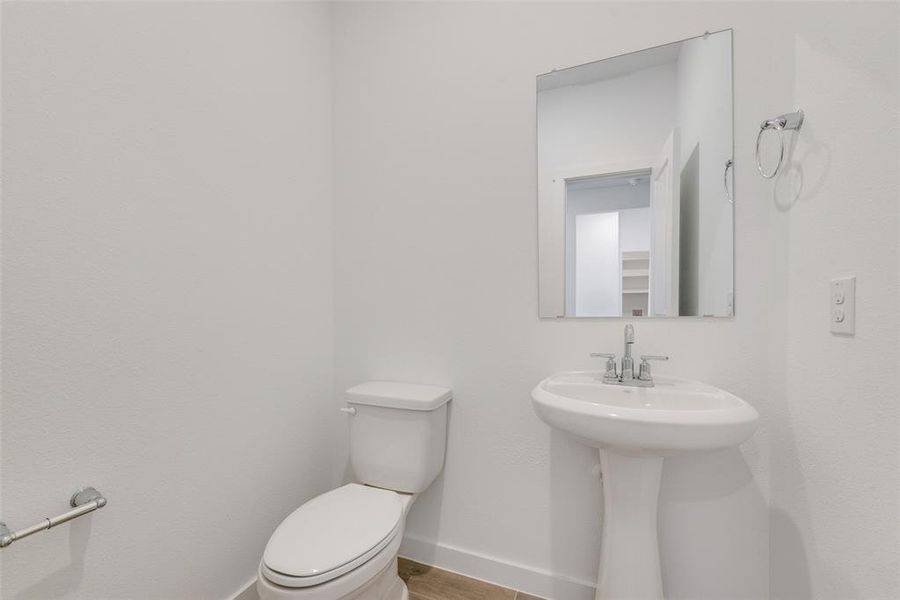 Bathroom featuring toilet, sink, and wood-type flooring