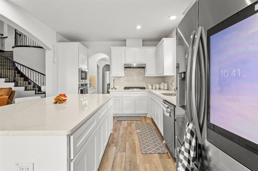 Kitchen featuring light hardwood / wood-style floors, sink, white cabinetry, backsplash, and appliances with stainless steel finishes