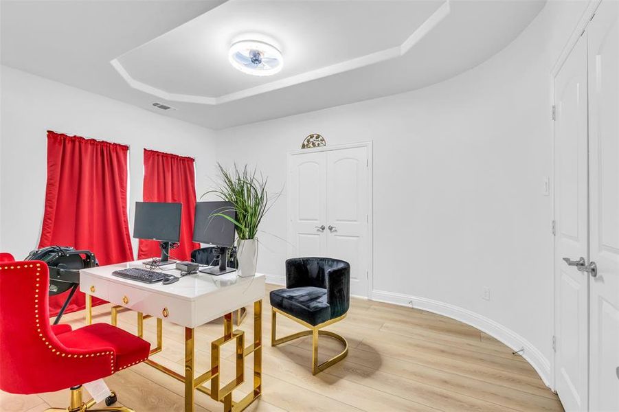 Office area with hardwood / wood-style flooring and a raised ceiling