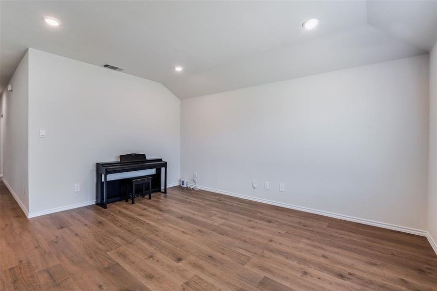 Unfurnished room with lofted ceiling and wood-type flooring