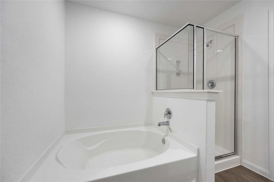 Primary ensuite bathroom with separate soaking tub and standing shower.