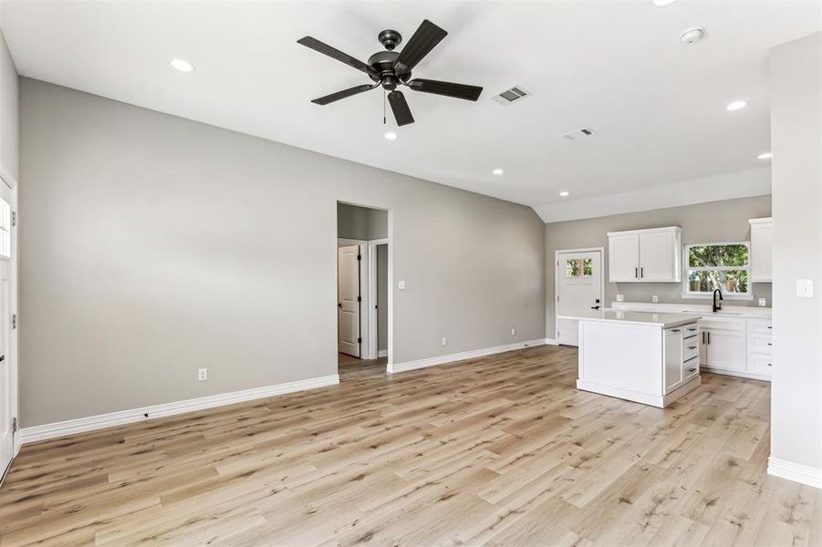 Kitchen with light wood-type flooring, a center island, ceiling fan, and white cabinets