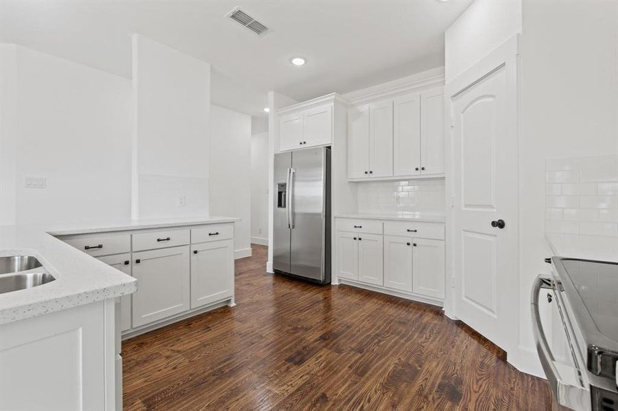 Kitchen featuring white cabinets, range, dark hardwood / wood-style floors, and stainless steel fridge with ice dispenser