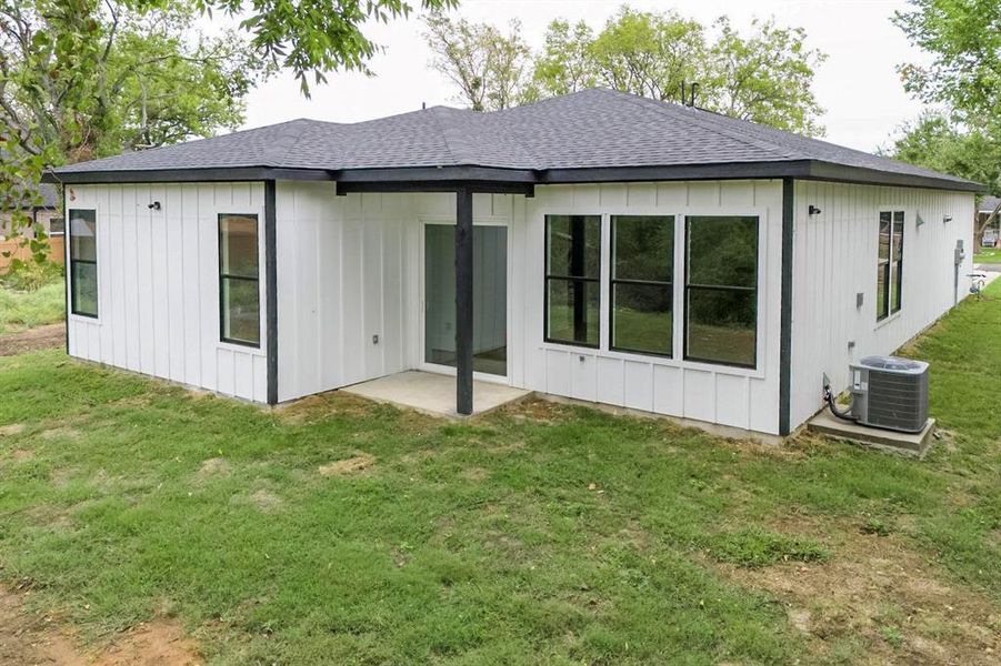 Rear view of house featuring central air condition unit, a patio, and a lawn