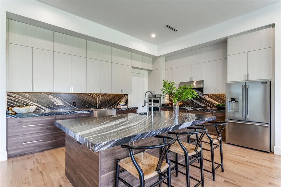 Kitchen with a spacious island, stainless steel fridge, light hardwood / wood-style flooring, and a breakfast bar area