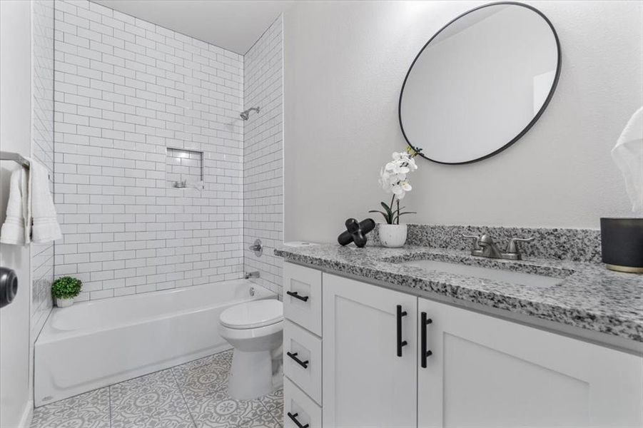 Full bathroom with tile patterned flooring, toilet, vanity, and tiled shower / bath