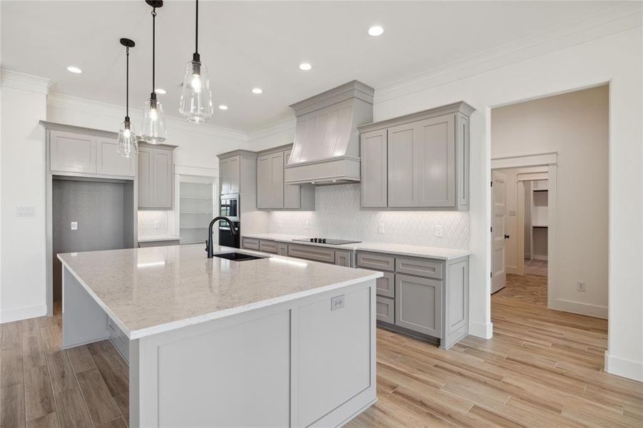 Kitchen with black electric stovetop, light hardwood / wood-style floors, light stone countertops, and sink