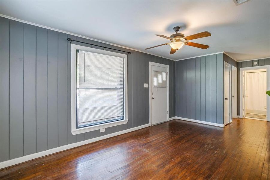 Entryway with dark wood-type flooring, ceiling fan, wood walls, and crown molding