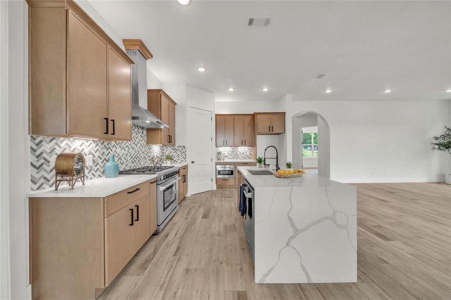 Kitchen featuring light hardwood / wood-style floors, sink, stainless steel appliances, and wall chimney exhaust hood